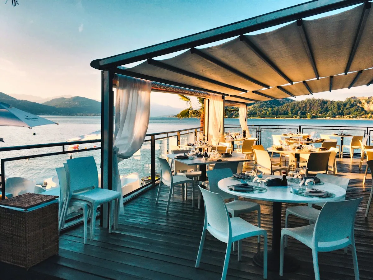 Taras restauracji nad wodą z zadaszeniem i nakrytymi stolikami